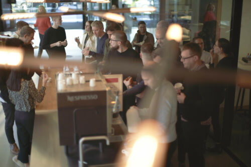 An overhead photo of Warren & Mahoney Staff socialising at a coffee machine